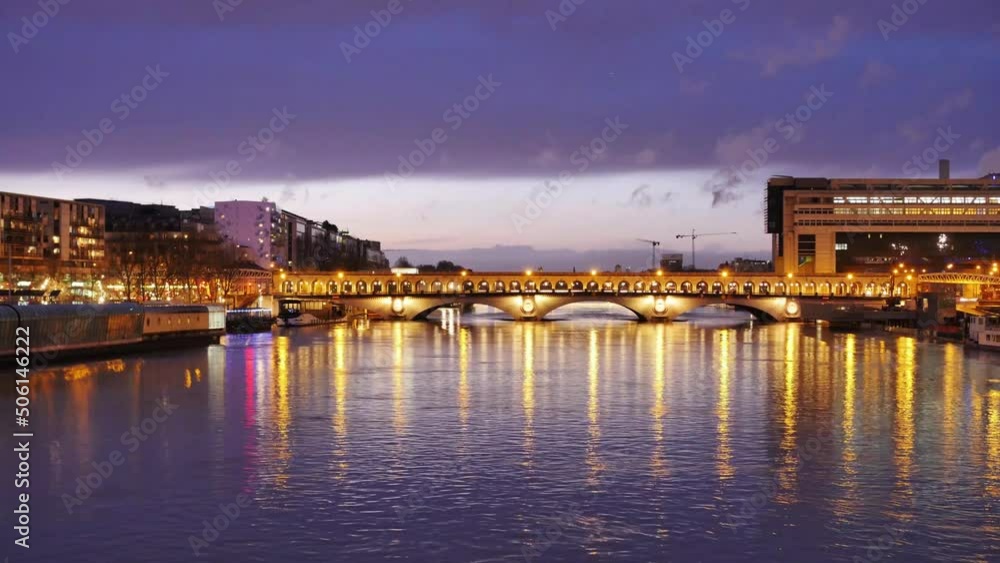 Time lapse. View of the Seine and the Pont de Bercy in Paris, in the 13th arrondissement. Above the bridge, the subway goes by. Filmed at sunset, colored lights reflecting in the water. Time lapse. View of the Seine and the Pont de Bercy in Paris, in the 13th arrondissement. Above the bridge, the subway goes by. Filmed at sunset, colored lights reflecting in the water.