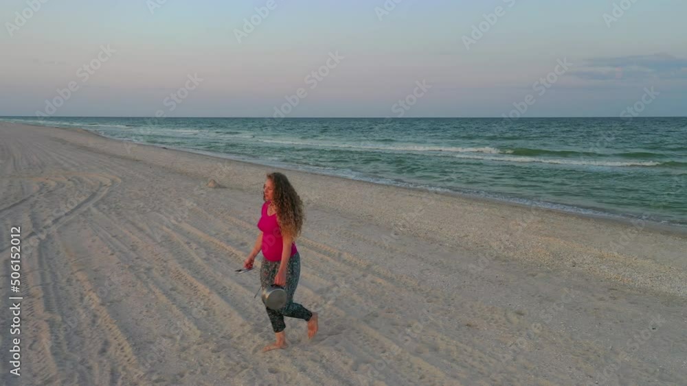 Camping on the seashore, a curly-haired girl washes dishes with sea sand against the backdrop of trailers and tents at sunset. pregnant girl Camping on the seashore, a curly-haired girl washes dishes with sea sand against the backdrop of trailers and tents at sunset. pregnant girl