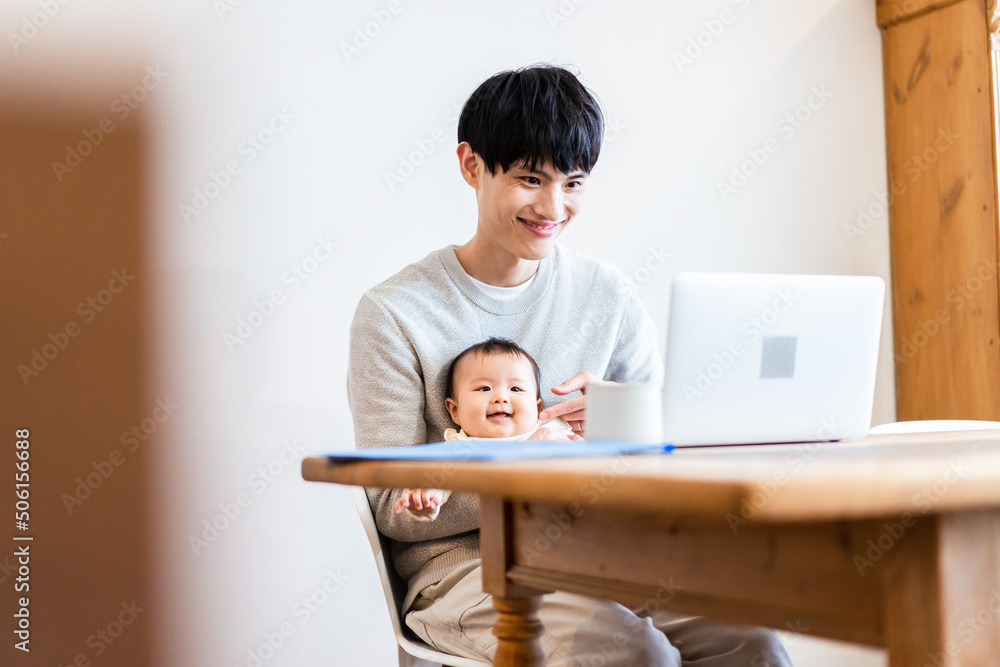 赤ちゃんをお世話しながら在宅勤務をするパパ