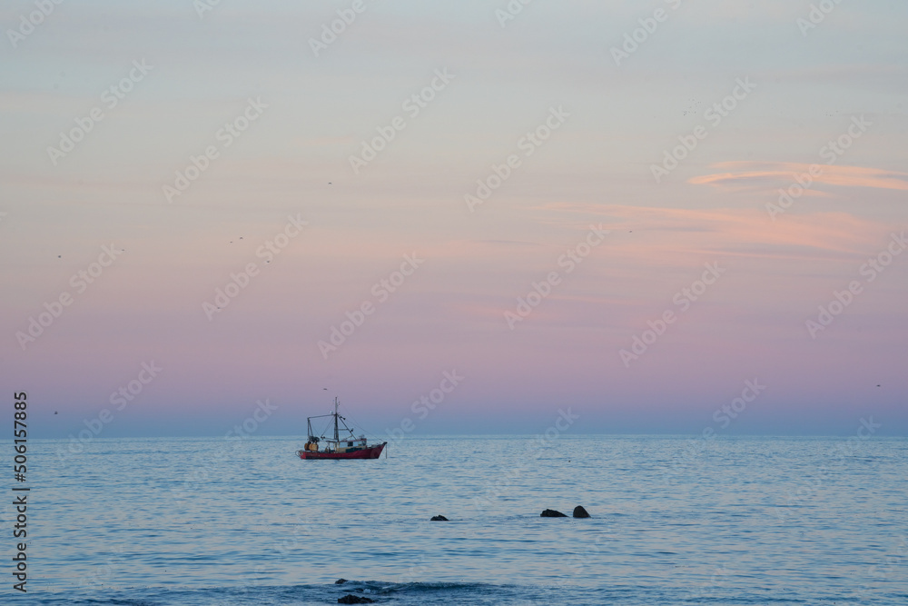 Fishing boat moored in bay at sunset