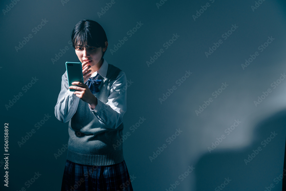 Fototapeta premium スマートフォンを見て不安になる女子高校生
