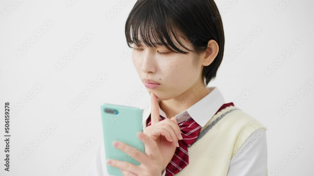 スマートフォンを持って困惑する女子高校生 スマートフォンを持って困惑する女子高校生