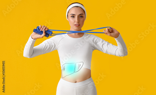 Sporty young woman with healthy liver on yellow background