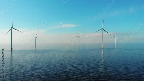 Windmill park in the ocean, drone aerial view of windmill turbines generating green energy electric, windmills isolated at sea in the Netherlands. High quality 4k footage