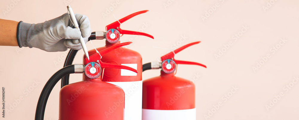 Close up fire extinguisher and firefighter checking pressure gauge level for protection and prevent and safety rescue and use of equipment on fire training concept. Close up fire extinguisher and firefighter checking pressure gauge level for protection and prevent and safety rescue and use of equipment on fire training concept.