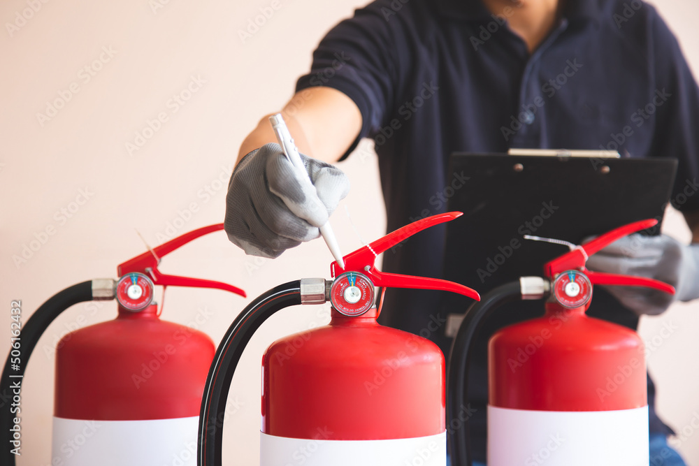 Close up fire extinguisher and firefighter checking pressure gauge level for protection and prevent and safety rescue and use of equipment on fire training concept. Close up fire extinguisher and firefighter checking pressure gauge level for protection and prevent and safety rescue and use of equipment on fire training concept.