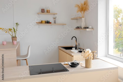 Interior of light kitchen with electric stove and utensils