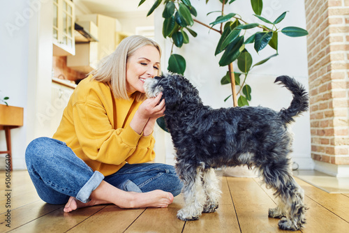 Smiling woman playing with her dog indoors