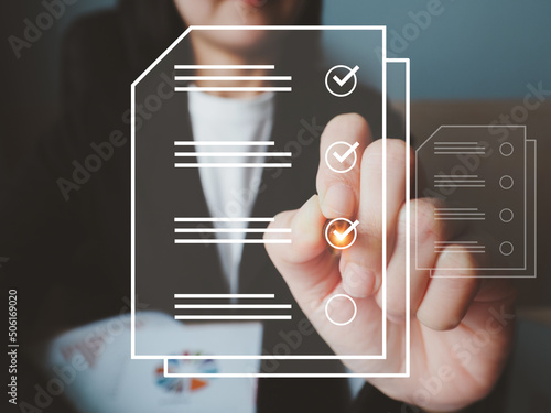 A businesswoman taking an online quiz or questionnaire icon on a digital window providing insightful work satisfaction information. Document Approval Check photo