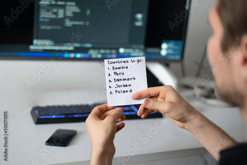 person holding a paper note with countries to visit list