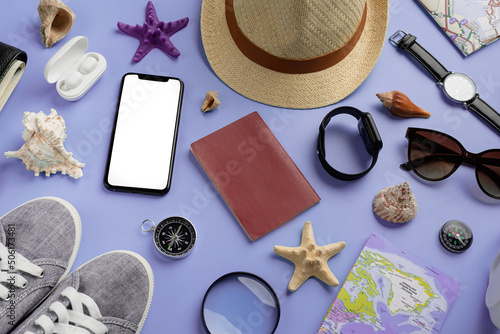 Top view travel accessories with shoes, map, smartphone with mockup screen, hat on very peri purple background