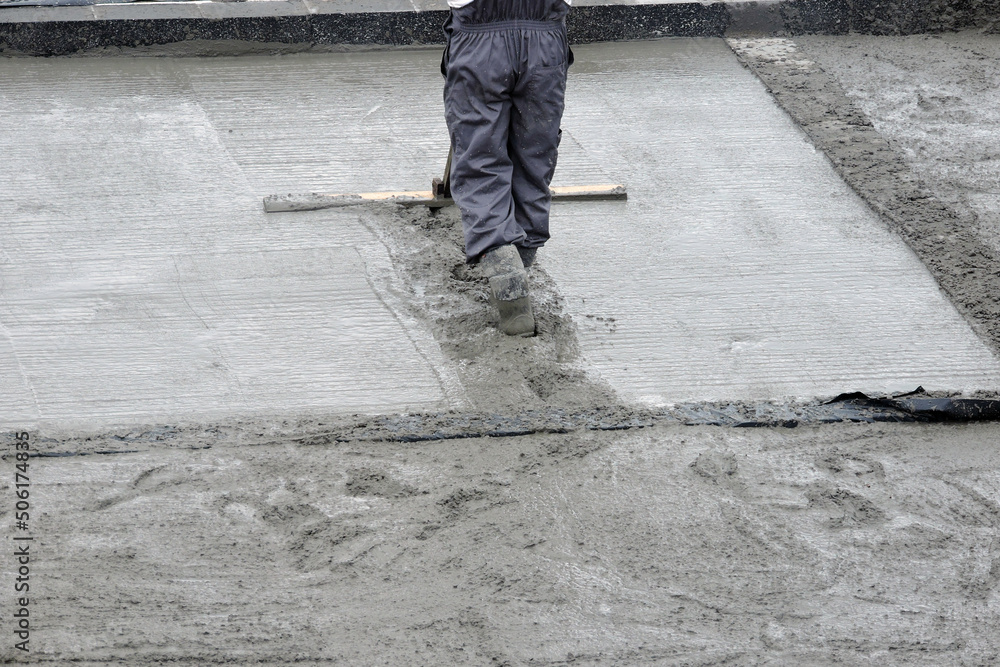 A building worker bull-floating the wet concrete
A building worker bull-floating the wet concrete