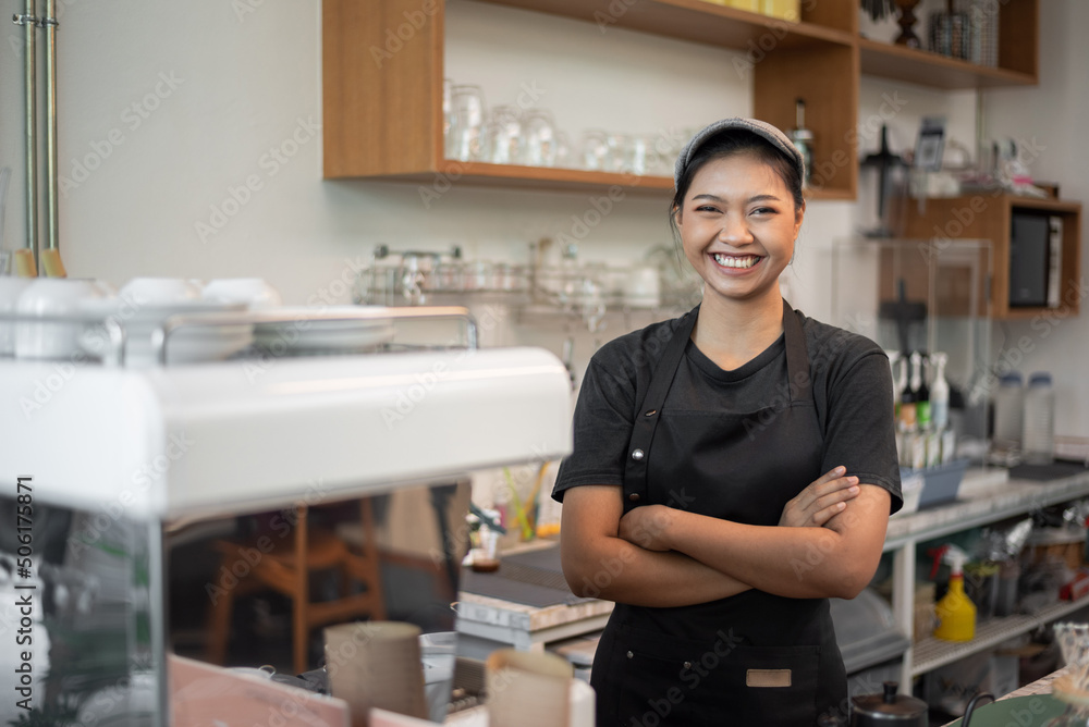 Asian woman Barista smiling and standing in coffee shop. female barista standing behind counter in cafe.