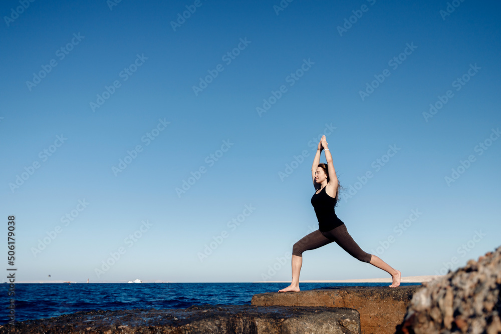 Young woman practicing yoga healthy life, meditation background sea blue water. Concept different asana on beautiful landscape Young woman practicing yoga healthy life, meditation background sea blue water. Concept different asana on beautiful landscape