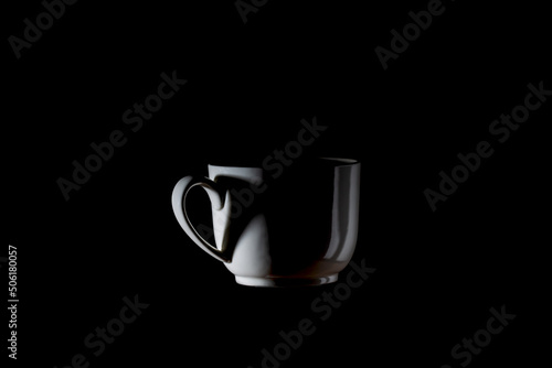 Cup of coffee and heart-shaped shadow with smoke on black background, This photo is available without smoke, drinking concept.