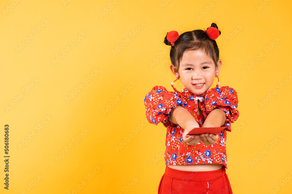 Chinese New Year. Happy Asian Chinese little girl smile wear red cheongsam handed angpao or red packet monetary gift, Portrait children in traditional dress, studio short isolated on yellow background Chinese New Year. Happy Asian Chinese little girl smile wear red cheongsam handed angpao or red packet monetary gift, Portrait children in traditional dress, studio short isolated on yellow background
