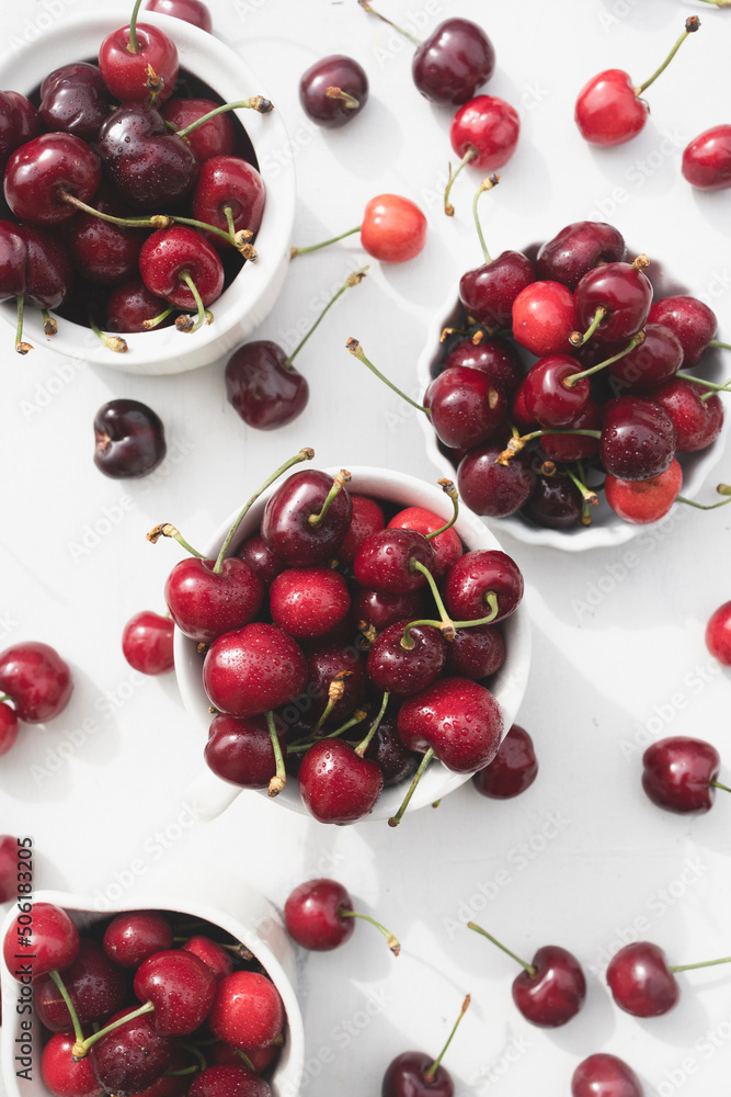 Delicious cherries in white ceramic cups on a white wood table Delicious cherries in white ceramic cups on a white wood table