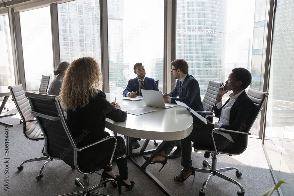 Group of successful young multi ethnic businesspeople partners gathered in modern office boardroom to solve common business, work on collaborative project, strategizing together. Negotiation concept Group of successful young multi ethnic businesspeople partners gathered in modern office boardroom to solve common business, work on collaborative project, strategizing together. Negotiation concept