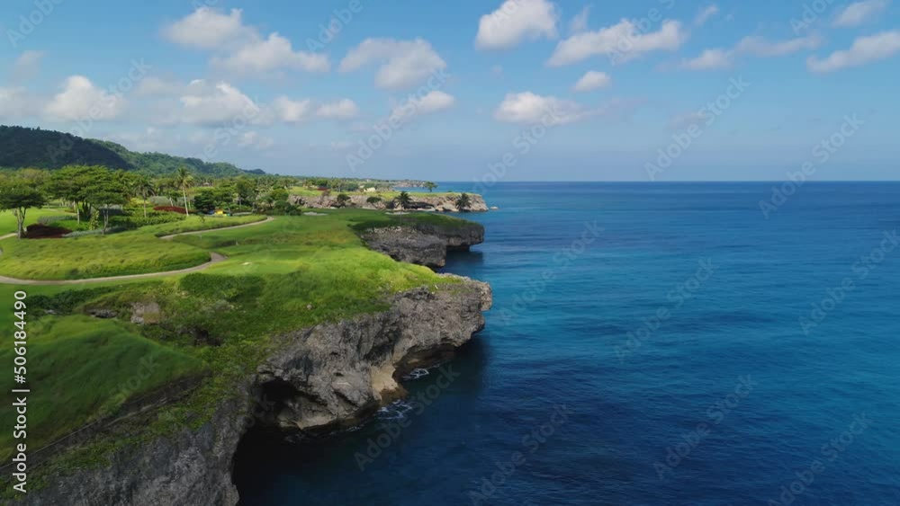Beautiful seascape of Dominican nature on a sunny summer day. A green peninsula with a rocky coast in a bright blue sea. Blue cloudy sky over tropical sea coast. Travel to tropical paradise.