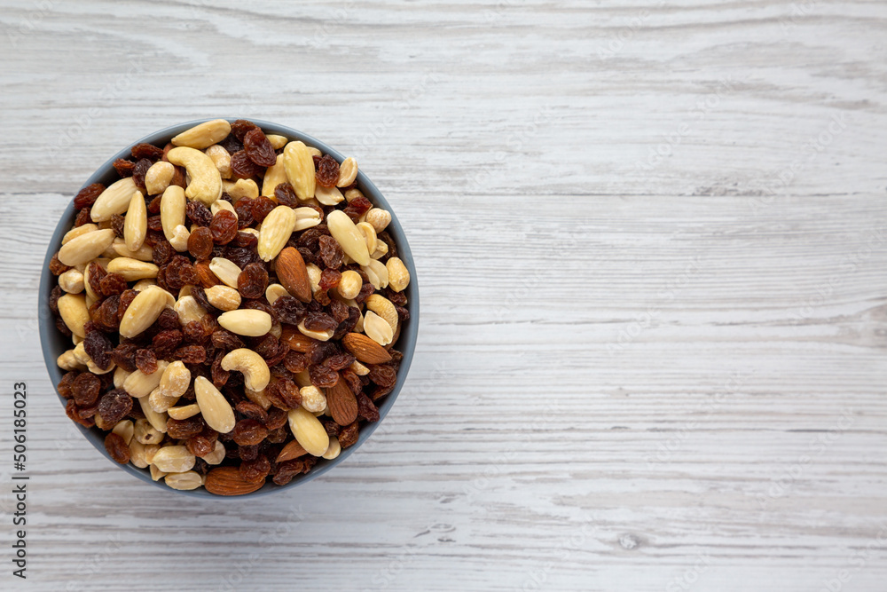 Raw Trail Mix with Nuts and Fruits in a Bowl on a white wooden background, top view. Flat lay, overhead, from above. Space for text. Raw Trail Mix with Nuts and Fruits in a Bowl on a white wooden background, top view. Flat lay, overhead, from above. Space for text.
