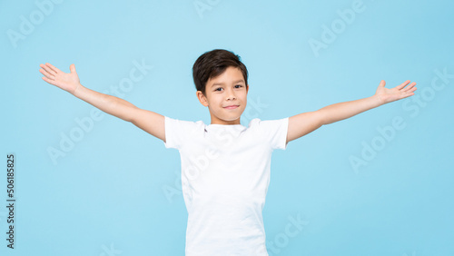 Billede på lærred Cute smiling handsome mixed race boy with open arms in isolated light blue color