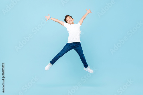 Wallpaper Mural Energetic Asian mixed race boy jumping and raising hands up in isolated light blue color studio background Torontodigital.ca