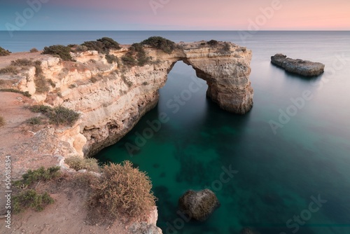 Natural arch above ocean, arco de Albandeira, Algarve, Lagoa portugal. Stone arch at beach. Summer season.