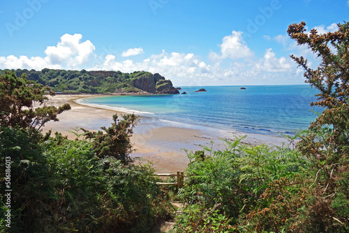 A beautiful panoramic view of Ouaisne Bay with verdant scenery and cliffs with blue sea and blue sky and fluffy white clouds sky in Jersey in the beautiful Channel Islands U.K.