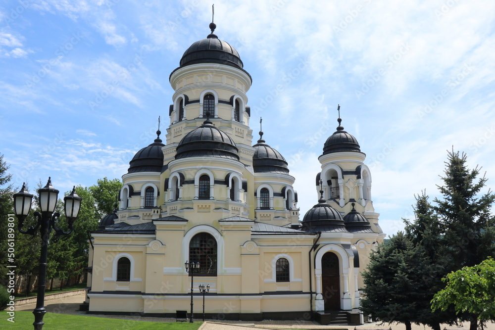 A large cathedral with black domes in the monastery. Beautiful church in a green park