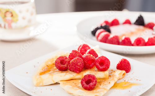 breakfast of pancakes with fresh raspberries on table
