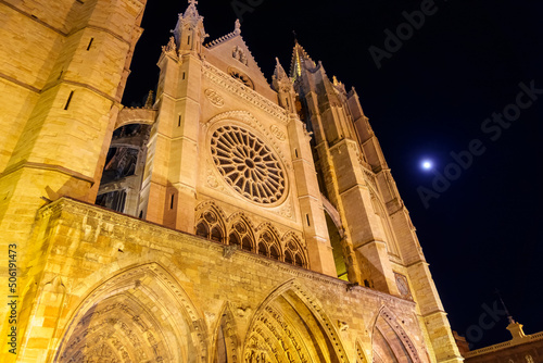 Night photo of Leon Cathedral with the moon in the clear sky.