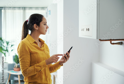 Woman managing her smart boiler using her phone