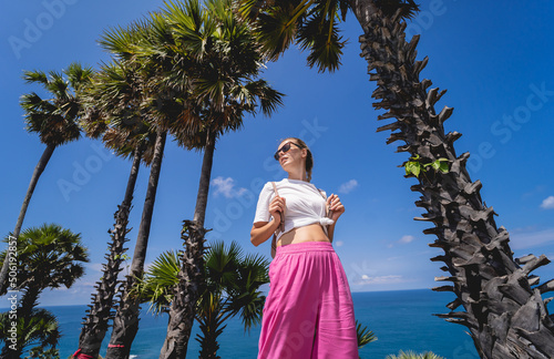 Young traveler woman at summer holiday vacation with beautiful palms and seascapes