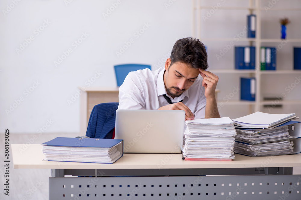 Young male employee and too much work in the office Young male employee and too much work in the office