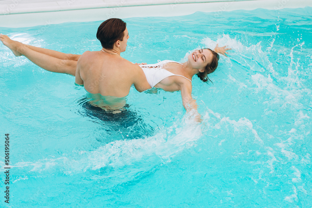 Young attractive couple are having rest in swimming pool. Enjoying the company of each other.
