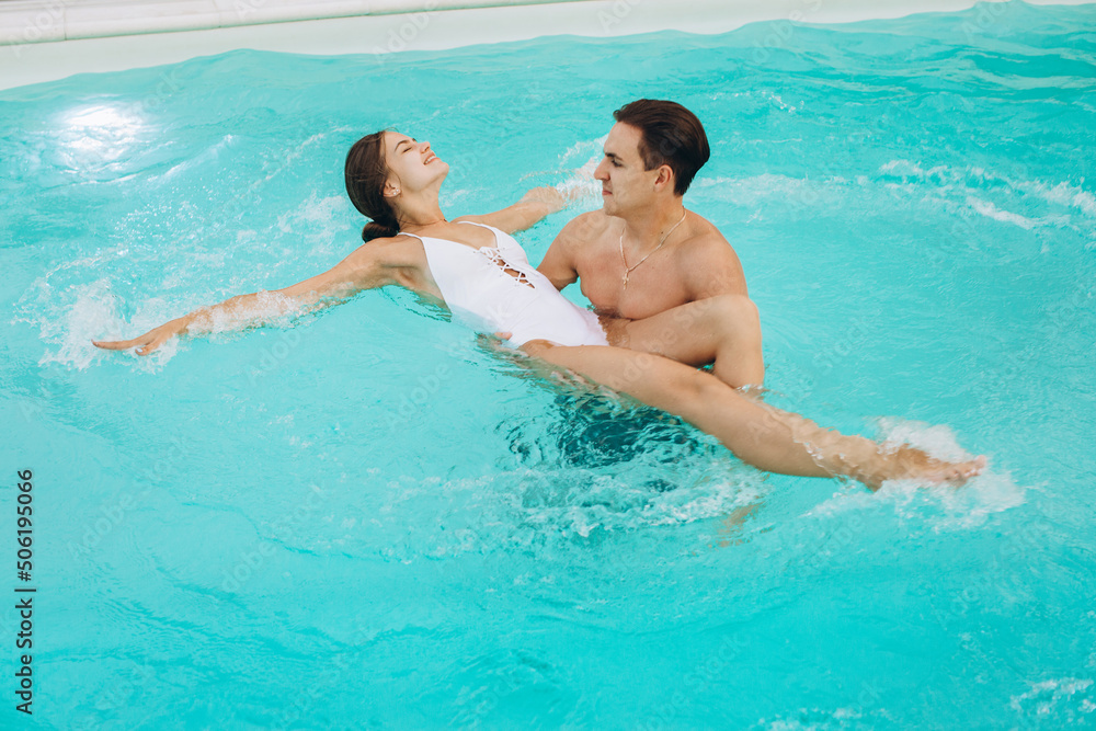 Young attractive couple are having rest in swimming pool. Enjoying the company of each other.