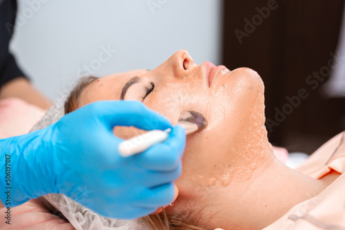 The girl at the beautician makes spa treatments, massage, facial cleansing and a mask for the skin. Cosmetic procedures in a beauty salon, facial skin care for rejuvenation.