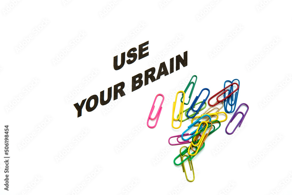inscription use your brain on a white background, next to it are multi-colored paper clips