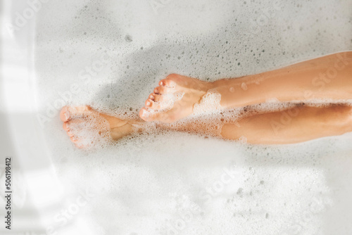 Feet of woman in bubble bath relaxing. Female Leg In Soapy Bath.