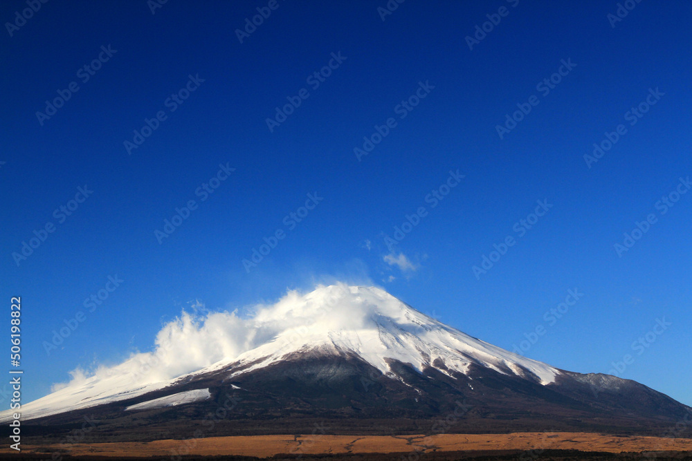 Fuji mountain with snow and fog covered top and clear blue sky background with above copy space. This mountain or place famous in Japan and Asia for people travel to visit and take picture. Natural 