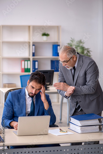 Old male boss and young male employee working in the office