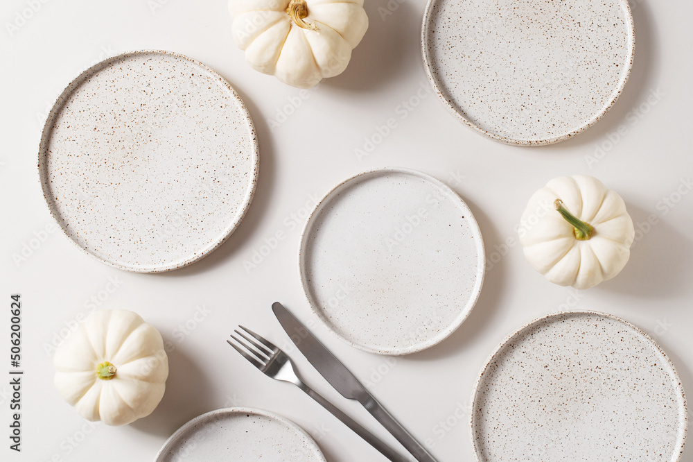 Some white ceramic plates with tableware and pumpkins serving background - obrazy, fototapety, plakaty 