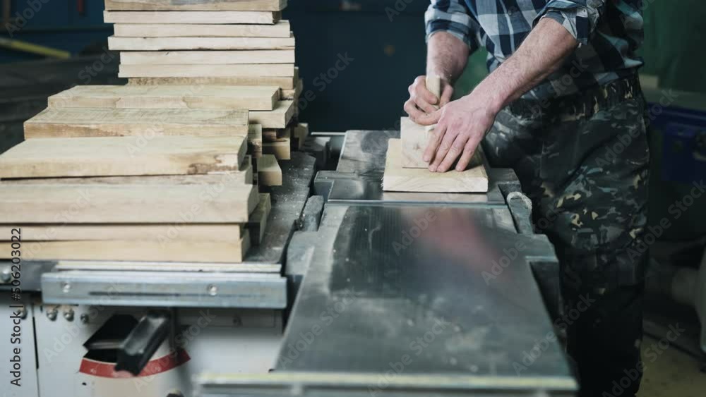 Close-up of hands and wood workpiece on planer. An unrecognizable man works as a carpenter. Close-up of hands and wood workpiece on planer. An unrecognizable man works as a carpenter.