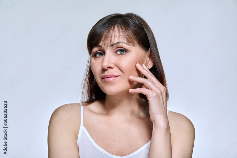 Portrait of middle aged woman looking at camera on light studio background Portrait of middle aged woman looking at camera on light studio background
