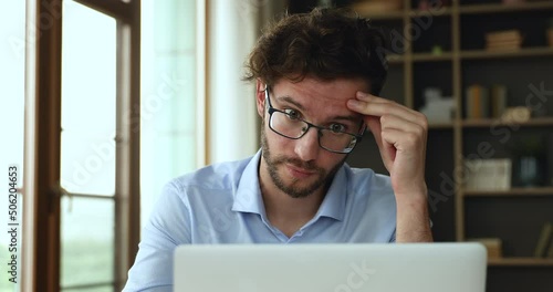 Man in glasses feels baffled having lack of understanding while working on laptop, learn new software, feeling physical or mental exhaustion caused by overwork or stress, information overload concept