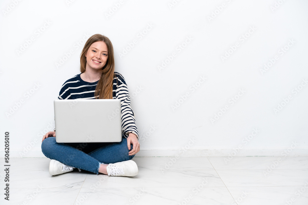 Young caucasian woman with a laptop sitting on the floor isolated on white background posing with arms at hip and smiling Young caucasian woman with a laptop sitting on the floor isolated on white background posing with arms at hip and smiling