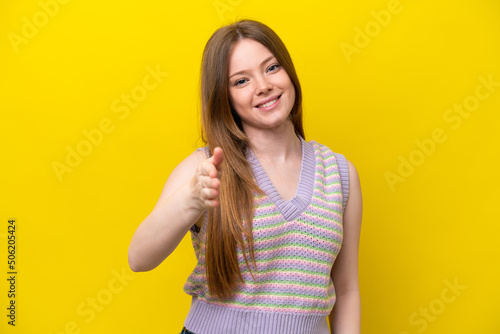 Young caucasian woman isolated on yellow background shaking hands for closing a good deal