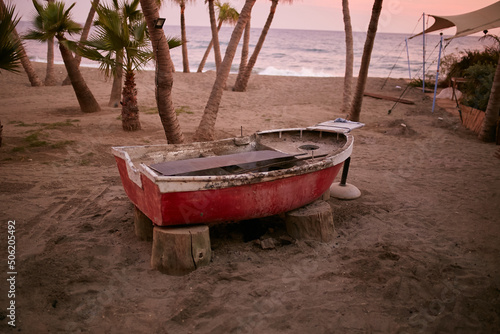Fototapeta Naklejka Na Ścianę i Meble -  Old wooden boat by the sea among palm trees.  