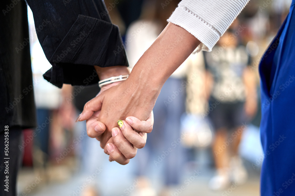 Lesbian couple holding hands in an urban night fair