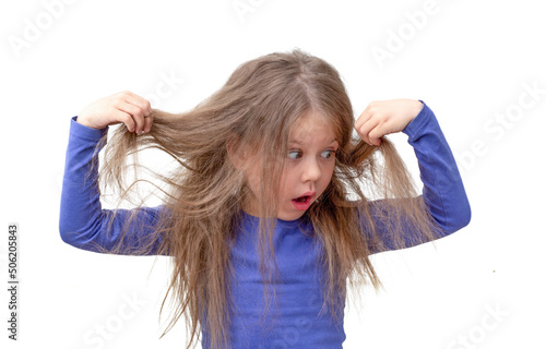 Isolated caucasian little girl of 5 6 years holding hair being in shock about hair losing or having lice on white background photo